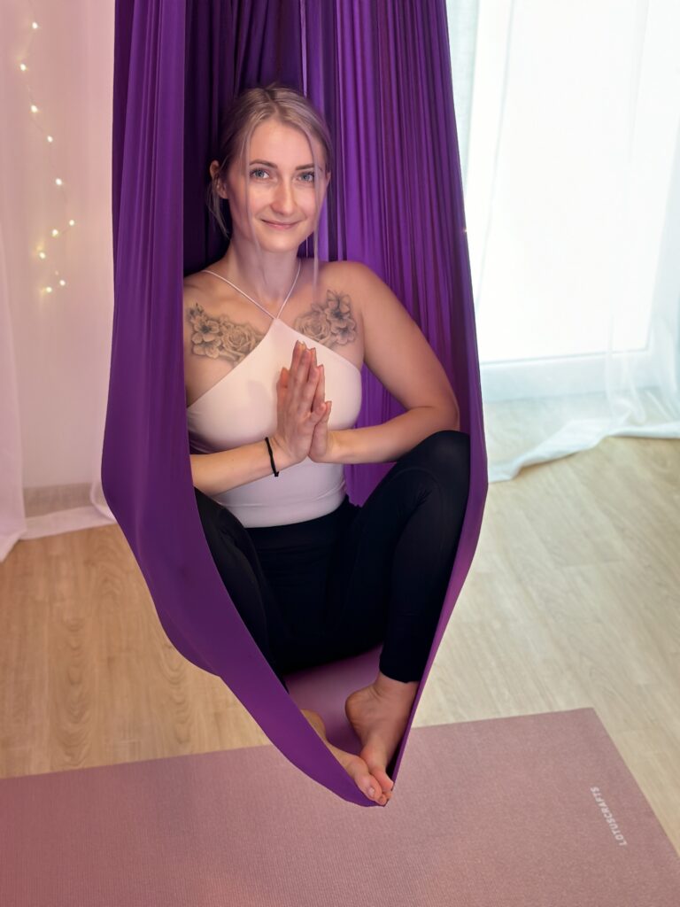 Lisa Enderlin sitzt beim Aerial Yoga in einem lila Hammock